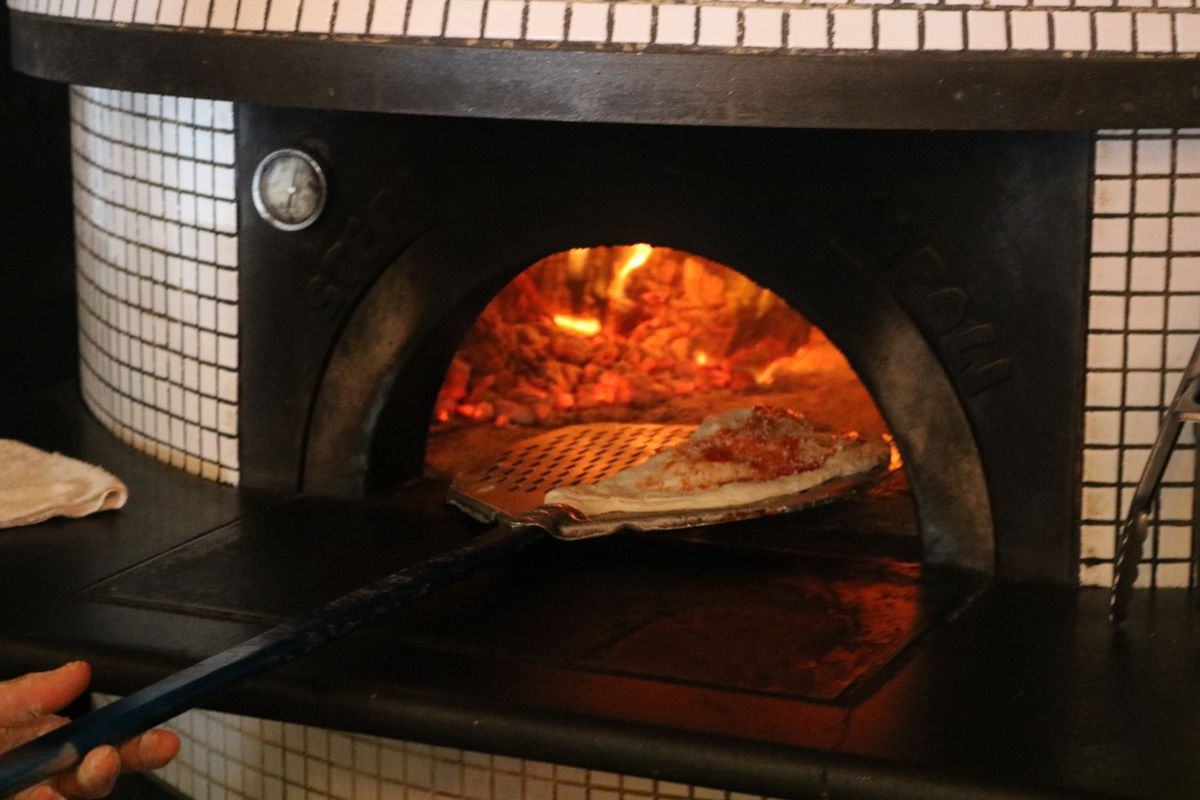 Pizzaïolo enfournant une pizza dans un four professionnel